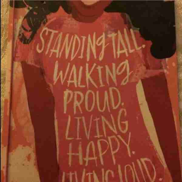 Woman wearing a shirt saying standing tall, walking proud, living happy, living loud