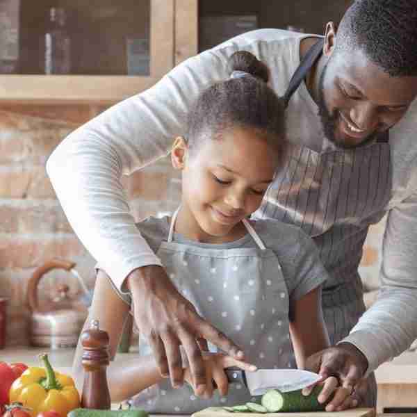 Father chopping vegetables with daughter