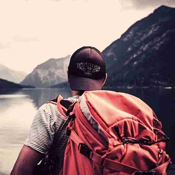man wearing backpack looking at the mountains proving travel is self care