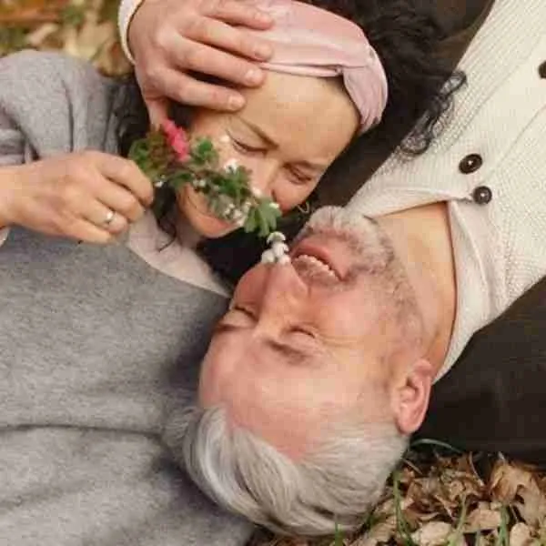woman tickling man with flower while lying on the ground showing how to heal your relationship with positivity