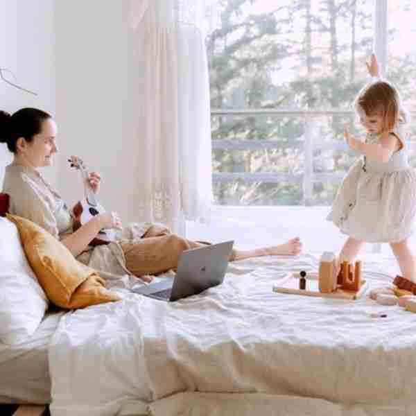 mother and daughter playing on a bed showing parenting positively