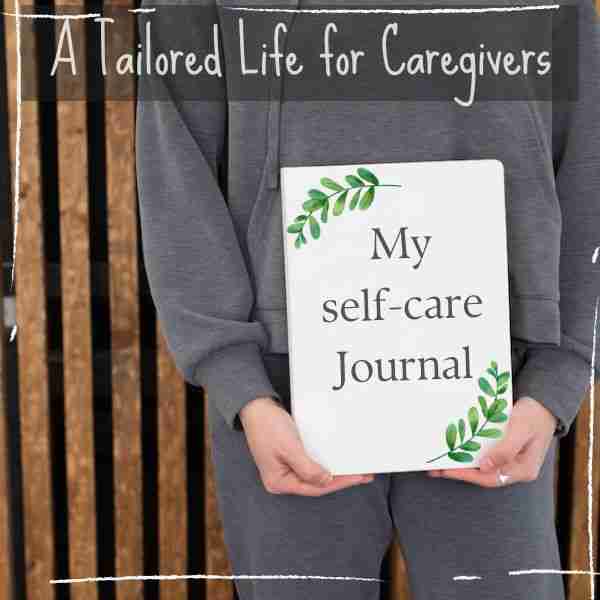 woman in a gray sweatshirt holding a self-care journal