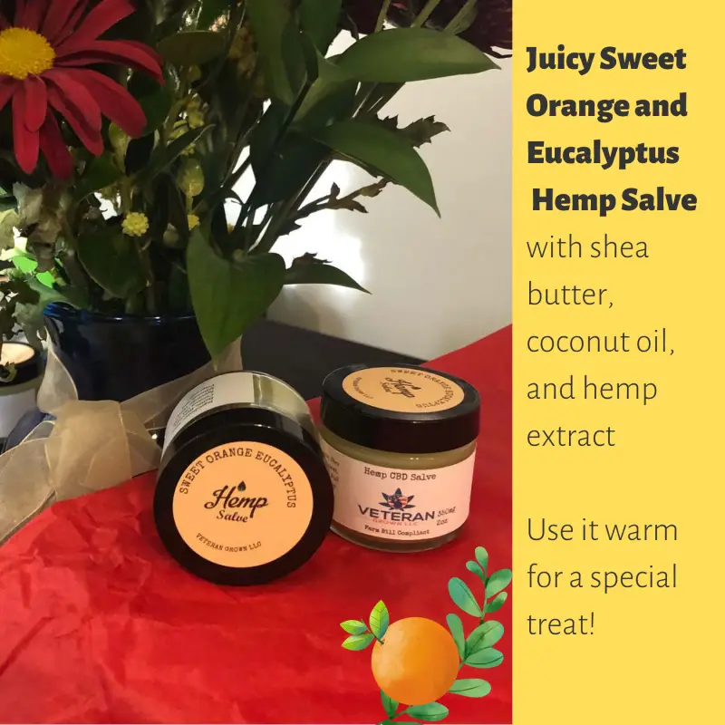 2 Jars of Sweet Orange and Eucalyptus Hemp Salve next to woodland flowers